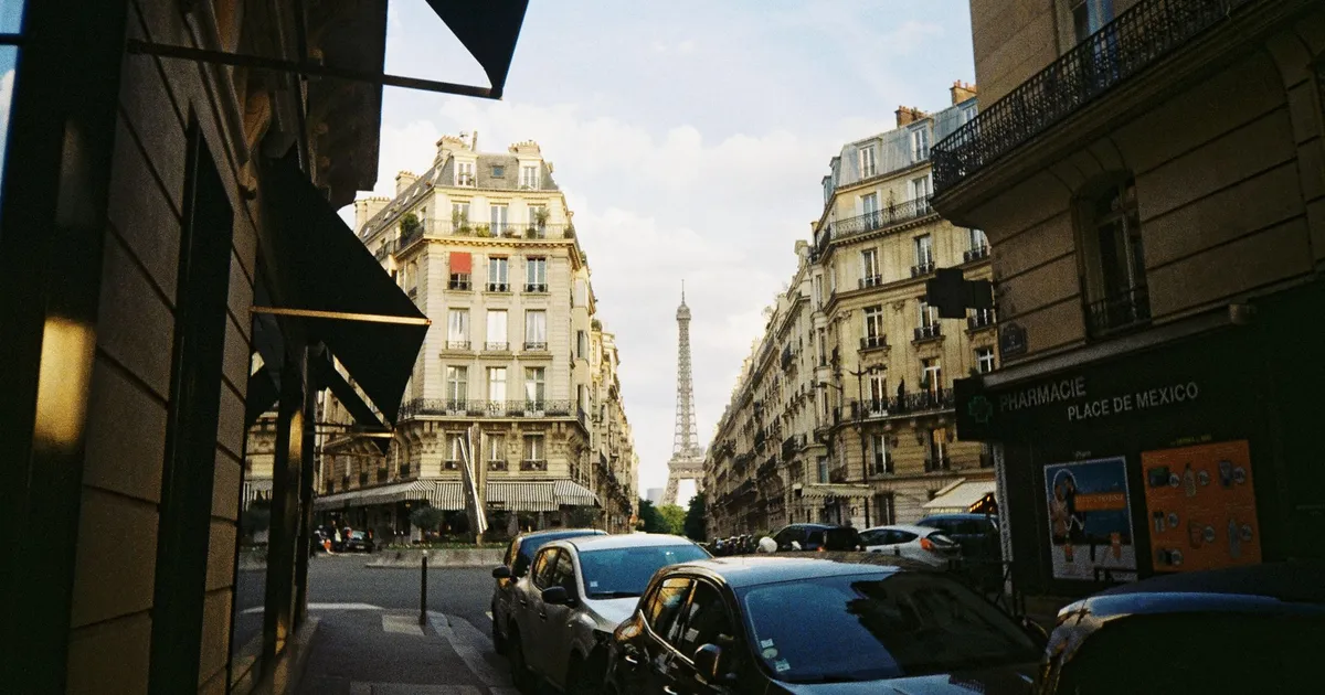 Rue parisienne bordée d'immeubles haussmanniens avec la tour Eiffel en arrière-plan